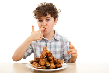 dítě olizující si prst s talířem plným grilovaného masa